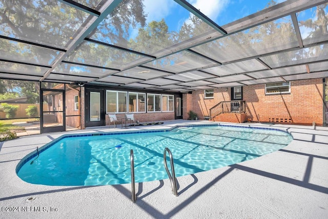 view of pool with glass enclosure and a patio area