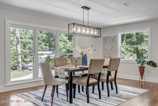 dining area featuring hardwood / wood-style flooring, a chandelier, and a textured ceiling