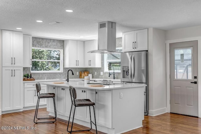 kitchen with island range hood, a center island, white cabinets, and light hardwood / wood-style floors