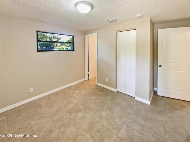 unfurnished bedroom with a textured ceiling and a closet