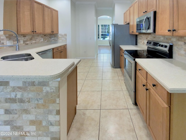 kitchen featuring sink, ornamental molding, appliances with stainless steel finishes, kitchen peninsula, and backsplash