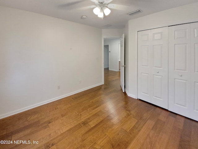 unfurnished bedroom with dark wood-type flooring, a closet, and ceiling fan