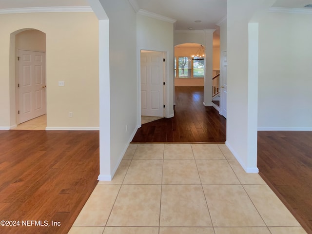 corridor featuring crown molding, a notable chandelier, and tile patterned floors