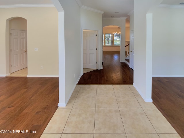 hall with light tile patterned flooring, a notable chandelier, and crown molding