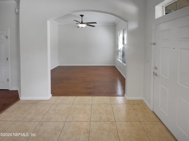 tiled entryway with crown molding and ceiling fan