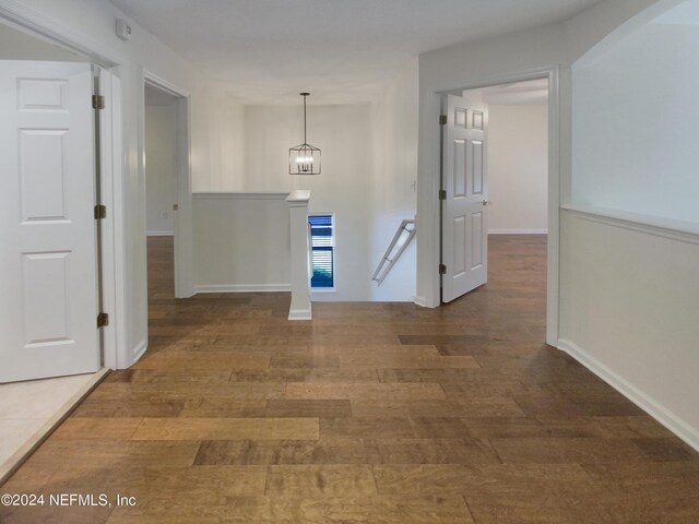 corridor with wood-type flooring and a notable chandelier