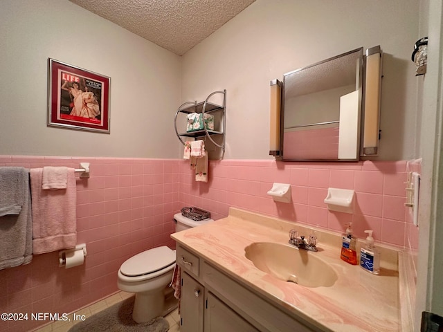 bathroom with tile patterned flooring, tile walls, toilet, a textured ceiling, and vanity