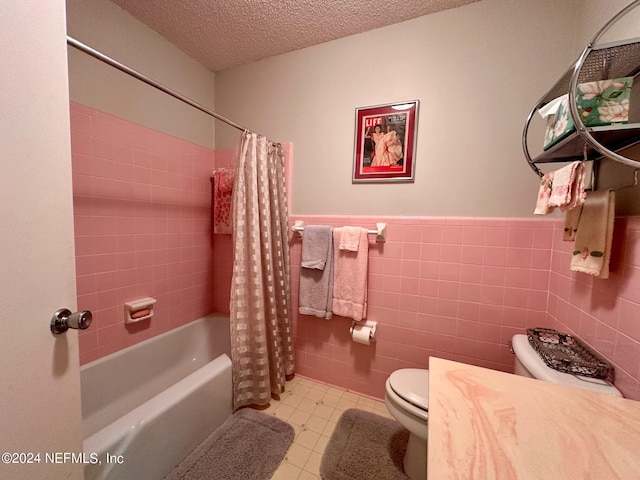 bathroom with a textured ceiling, toilet, shower / bathtub combination with curtain, and tile walls