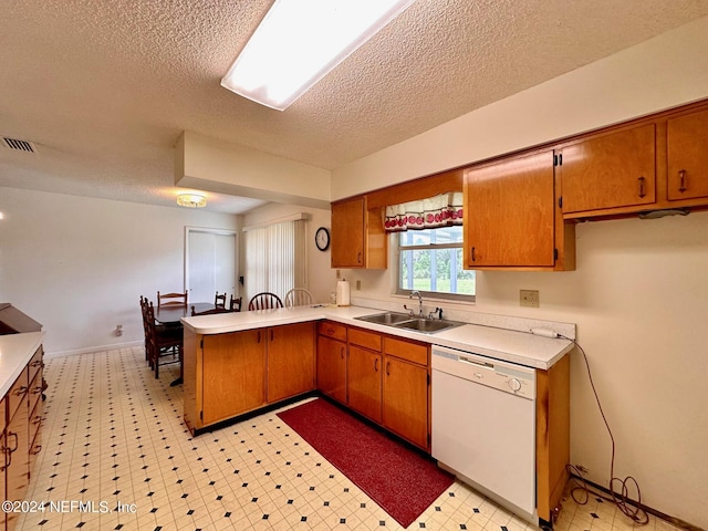 kitchen featuring sink, kitchen peninsula, white dishwasher, and a textured ceiling