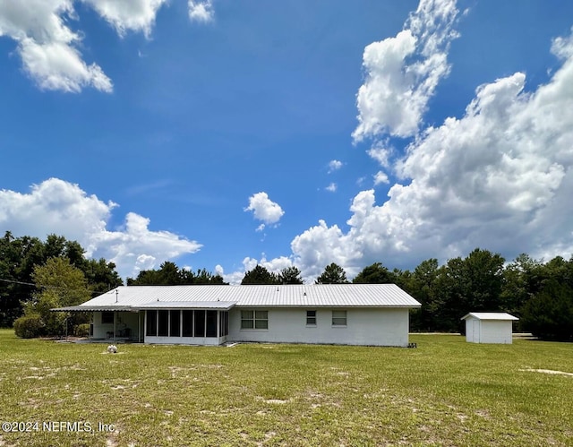 back of property with a yard, a storage shed, and a sunroom