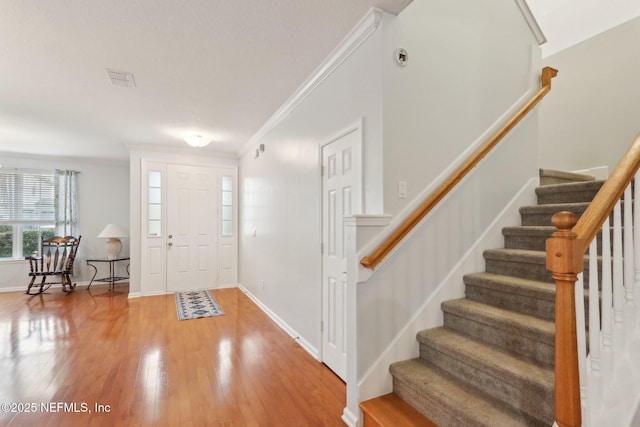 entryway with baseboards, stairs, ornamental molding, and wood finished floors