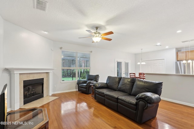 living area with a fireplace, wood finished floors, visible vents, and baseboards