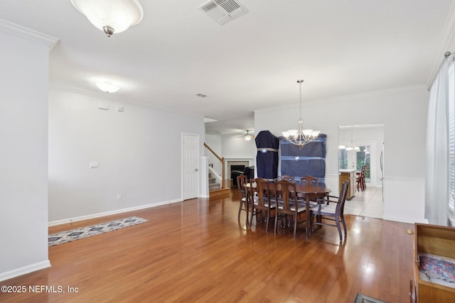 dining room with ornamental molding, wood finished floors, and visible vents