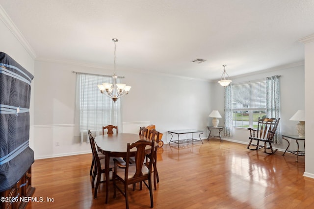 dining space featuring a chandelier, ornamental molding, and wood finished floors