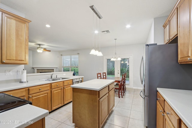 kitchen with a center island, light countertops, hanging light fixtures, appliances with stainless steel finishes, and a sink