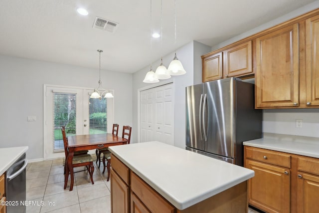 kitchen with visible vents, a kitchen island, stainless steel appliances, light countertops, and pendant lighting