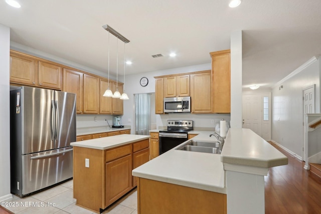 kitchen featuring appliances with stainless steel finishes, a center island, light countertops, and a peninsula