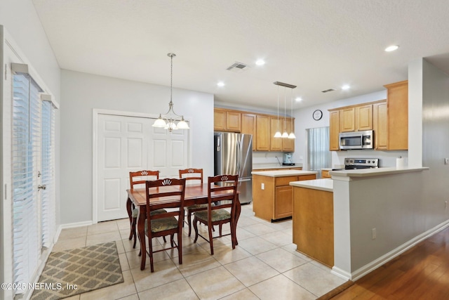 kitchen featuring pendant lighting, light countertops, visible vents, appliances with stainless steel finishes, and a peninsula