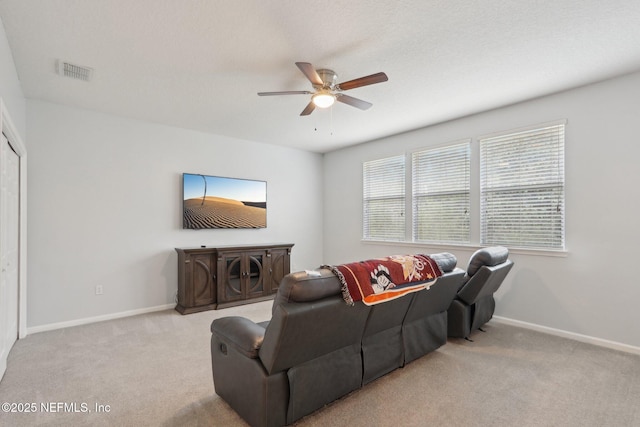 living room with a ceiling fan, visible vents, light carpet, and baseboards