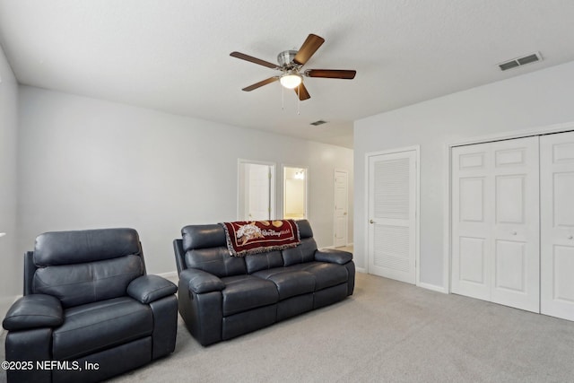 living area featuring a ceiling fan, visible vents, light carpet, and baseboards