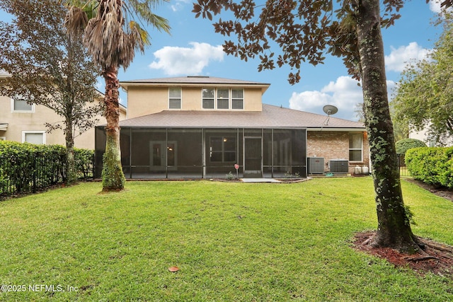 rear view of house with a lawn, a sunroom, a fenced backyard, central air condition unit, and stucco siding