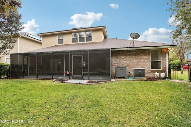 rear view of house with central air condition unit, brick siding, fence, and a lawn