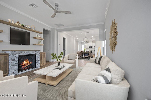 living room featuring hardwood / wood-style flooring, ceiling fan, ornamental molding, and a premium fireplace