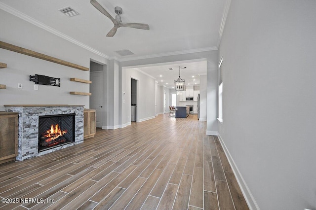 unfurnished living room with ceiling fan, ornamental molding, and a fireplace