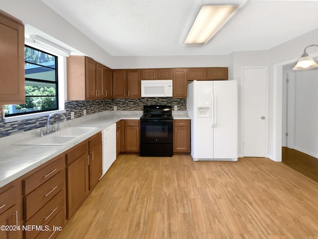 kitchen with white appliances, sink, decorative backsplash, and light wood-type flooring