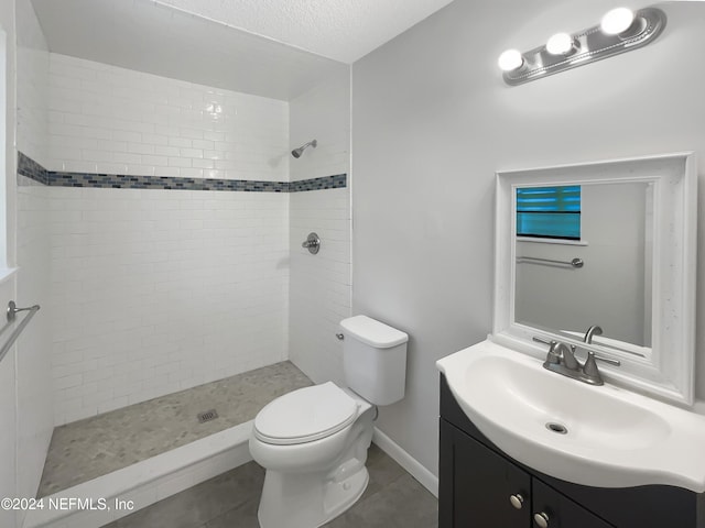 bathroom with vanity, tiled shower, a textured ceiling, and toilet