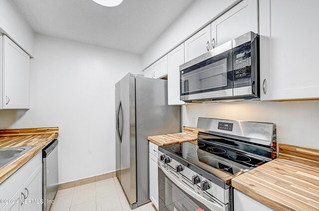 kitchen featuring white cabinets, stainless steel appliances, and butcher block counters