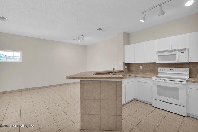 kitchen with track lighting, white appliances, sink, and kitchen peninsula