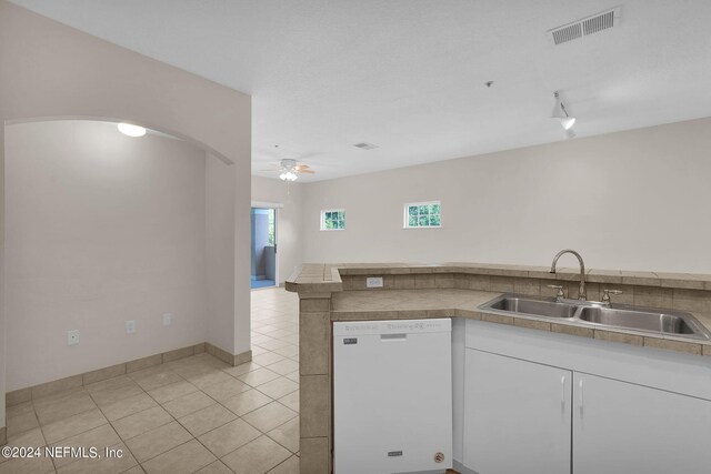 kitchen with white dishwasher, sink, light tile patterned floors, white cabinetry, and ceiling fan