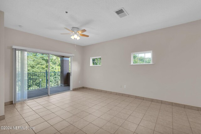 empty room featuring light tile patterned flooring, a textured ceiling, and ceiling fan