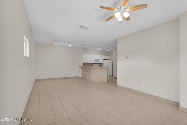 unfurnished living room featuring light tile patterned flooring, rail lighting, and ceiling fan