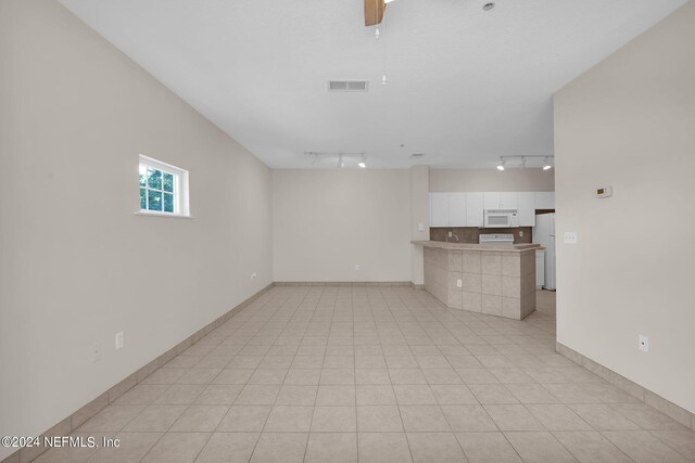 unfurnished living room featuring track lighting and light tile patterned floors