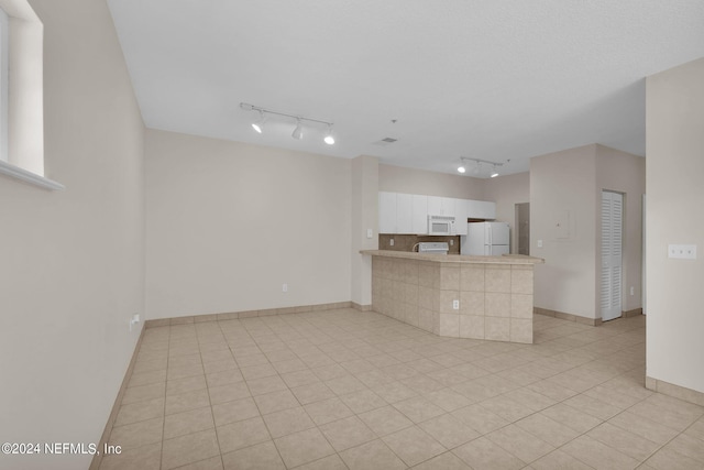 unfurnished living room featuring light tile patterned flooring and rail lighting