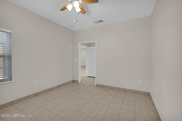 tiled spare room with ceiling fan