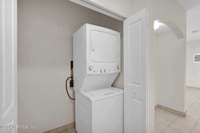 laundry room featuring light tile patterned flooring and stacked washer / dryer