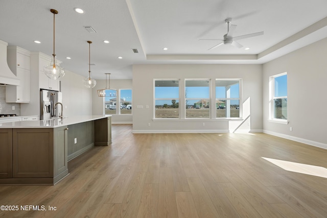 kitchen featuring decorative light fixtures, white cabinetry, a raised ceiling, ceiling fan, and light hardwood / wood-style flooring