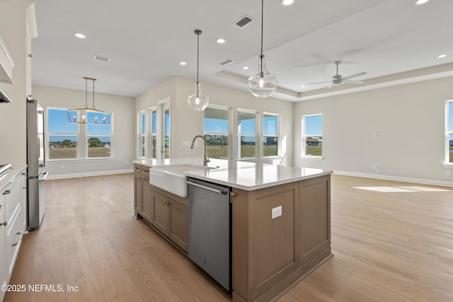 kitchen with sink, white cabinetry, an island with sink, a tray ceiling, and appliances with stainless steel finishes