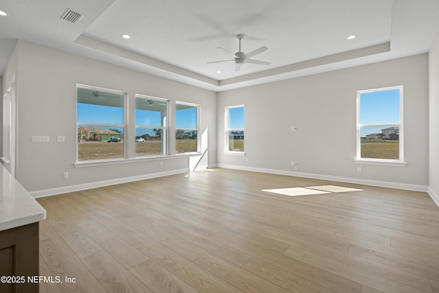 interior space with ceiling fan, light hardwood / wood-style flooring, and a raised ceiling