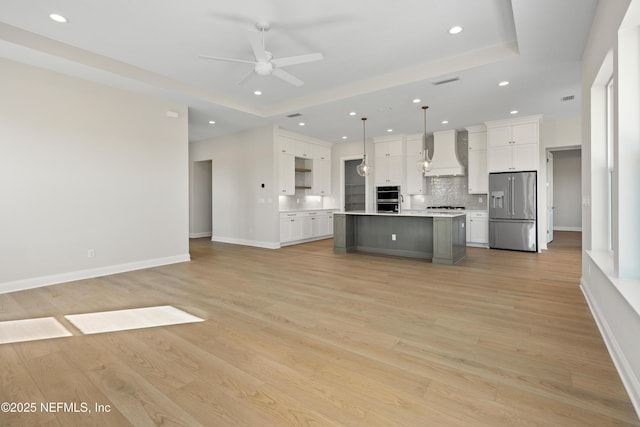 kitchen featuring appliances with stainless steel finishes, hanging light fixtures, custom range hood, a kitchen island, and white cabinetry