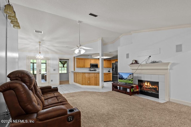 tiled living room with a tile fireplace, vaulted ceiling, and ceiling fan