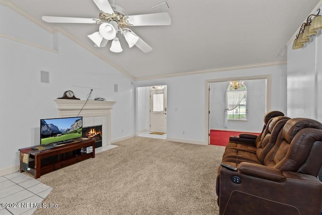 carpeted living room with a tiled fireplace, crown molding, lofted ceiling, and ceiling fan