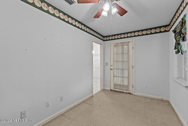 empty room featuring ceiling fan, light colored carpet, and a textured ceiling