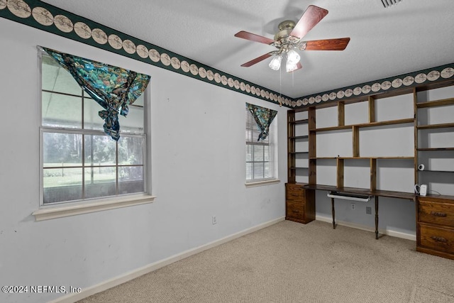 unfurnished bedroom featuring ceiling fan, light colored carpet, and a textured ceiling