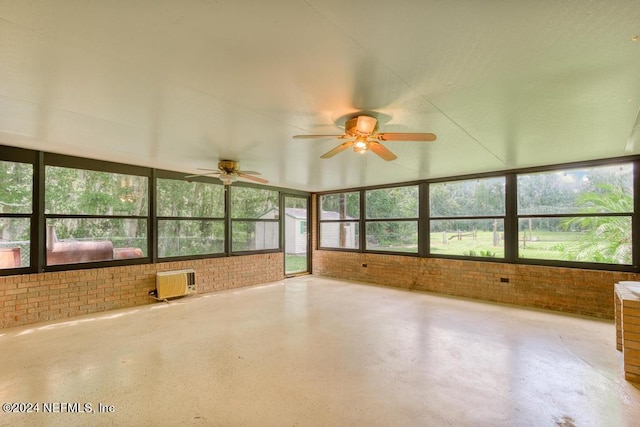 unfurnished sunroom featuring ceiling fan, plenty of natural light, and a wall mounted air conditioner