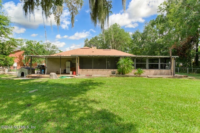 rear view of property featuring a yard, a patio area, and a sunroom