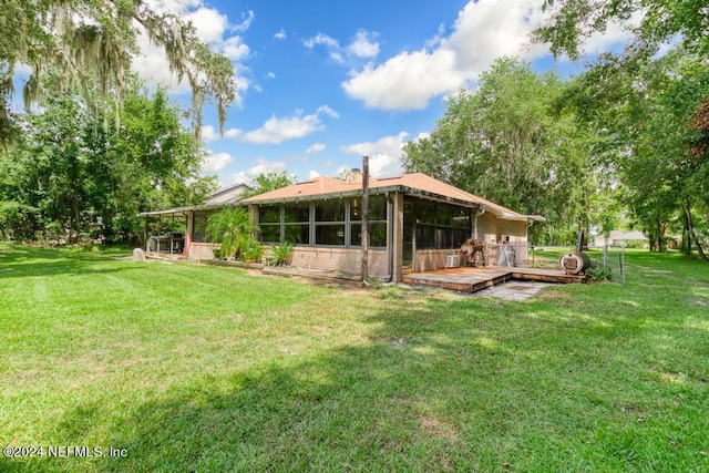 rear view of property with a yard, a sunroom, and a deck